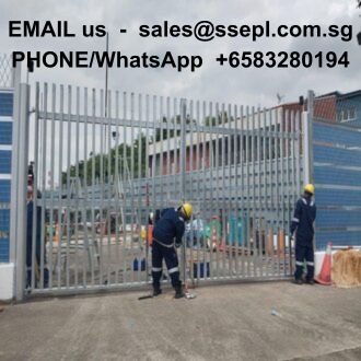 Two workers in hard hats and high-visibility gear stand beside a tall metal gate at an industrial site; contact email/phone text is overlaid at the top.