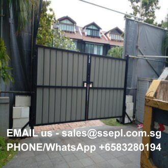 Construction site gate with corrugated panels; contact email and WhatsApp number overlaid at the bottom for inquiries.